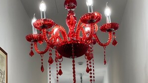 A hallway with a red chandelier and framed pictures on the walls.