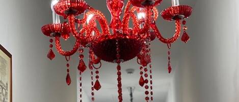 Un pasillo con un candelabro rojo e imágenes enmarcadas en las paredes.
