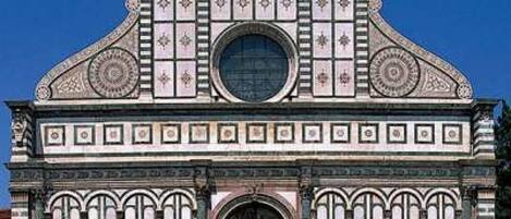 A historic building with a symmetrical facade, arched windows, and a central circular window.