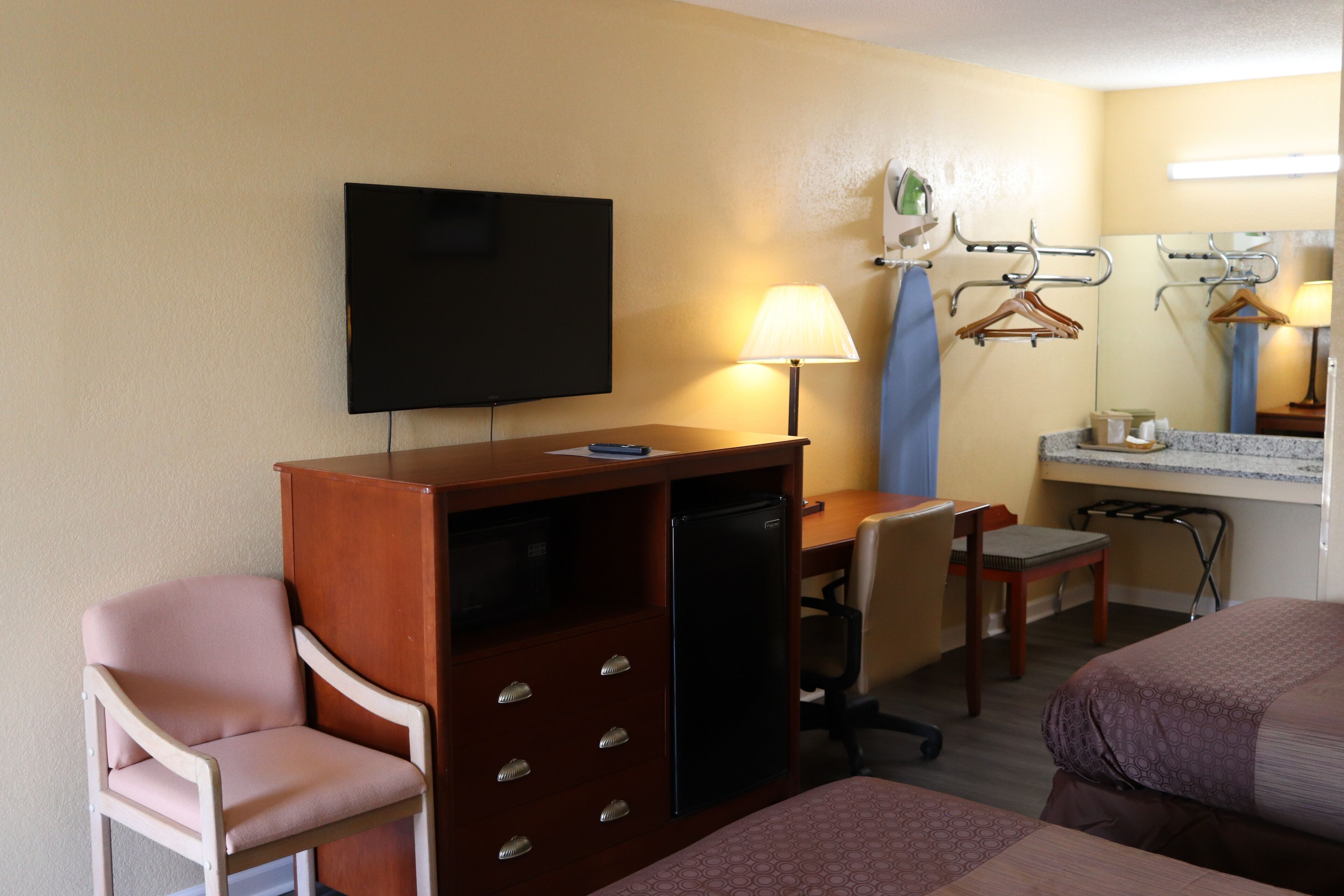 Quarto de hotel com televisão, secretária, cadeira e duas camas.