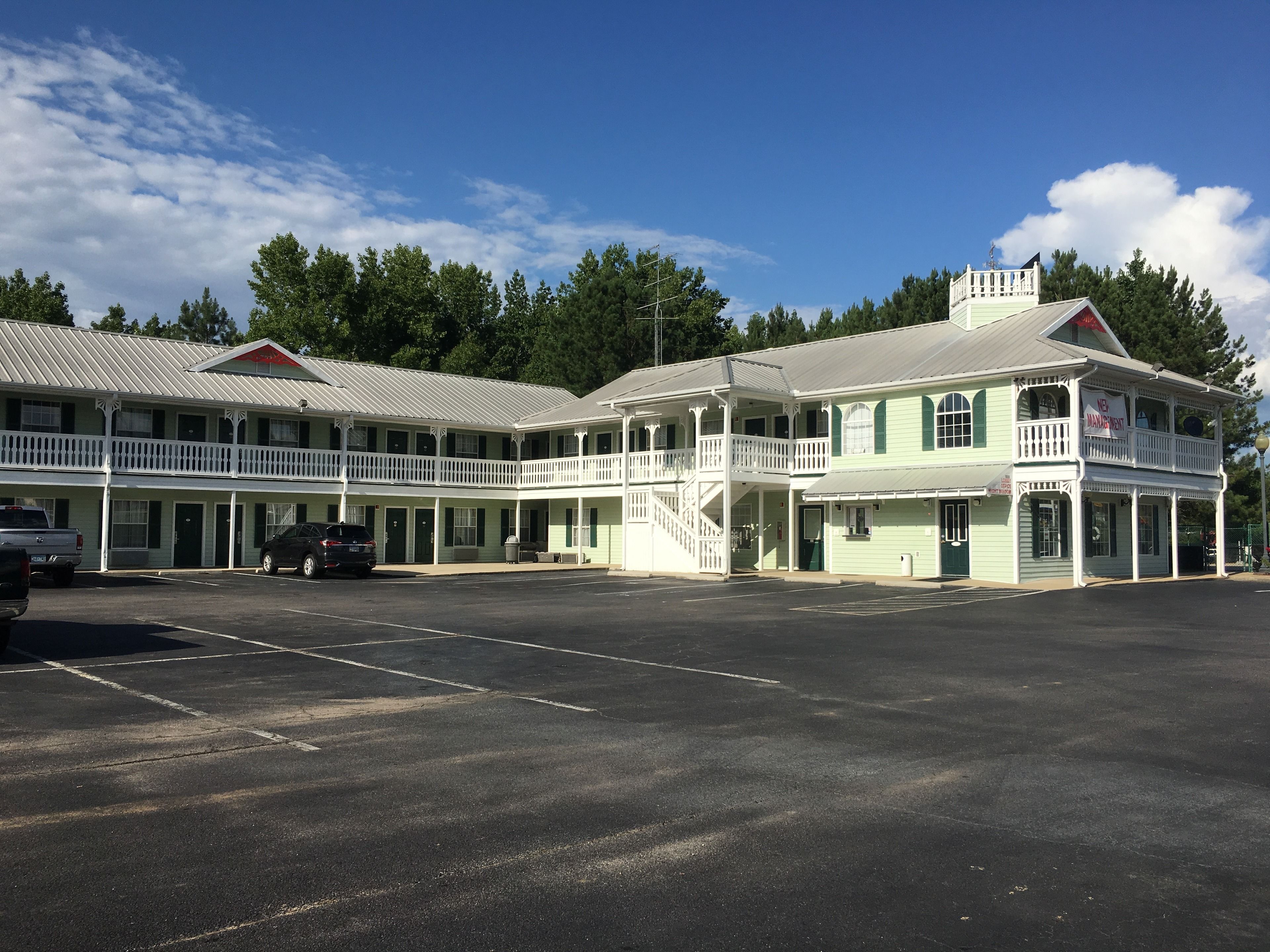 A two-story motel with a balcony on the second floor, a covered parking area, and a staircase leading to the upper level.