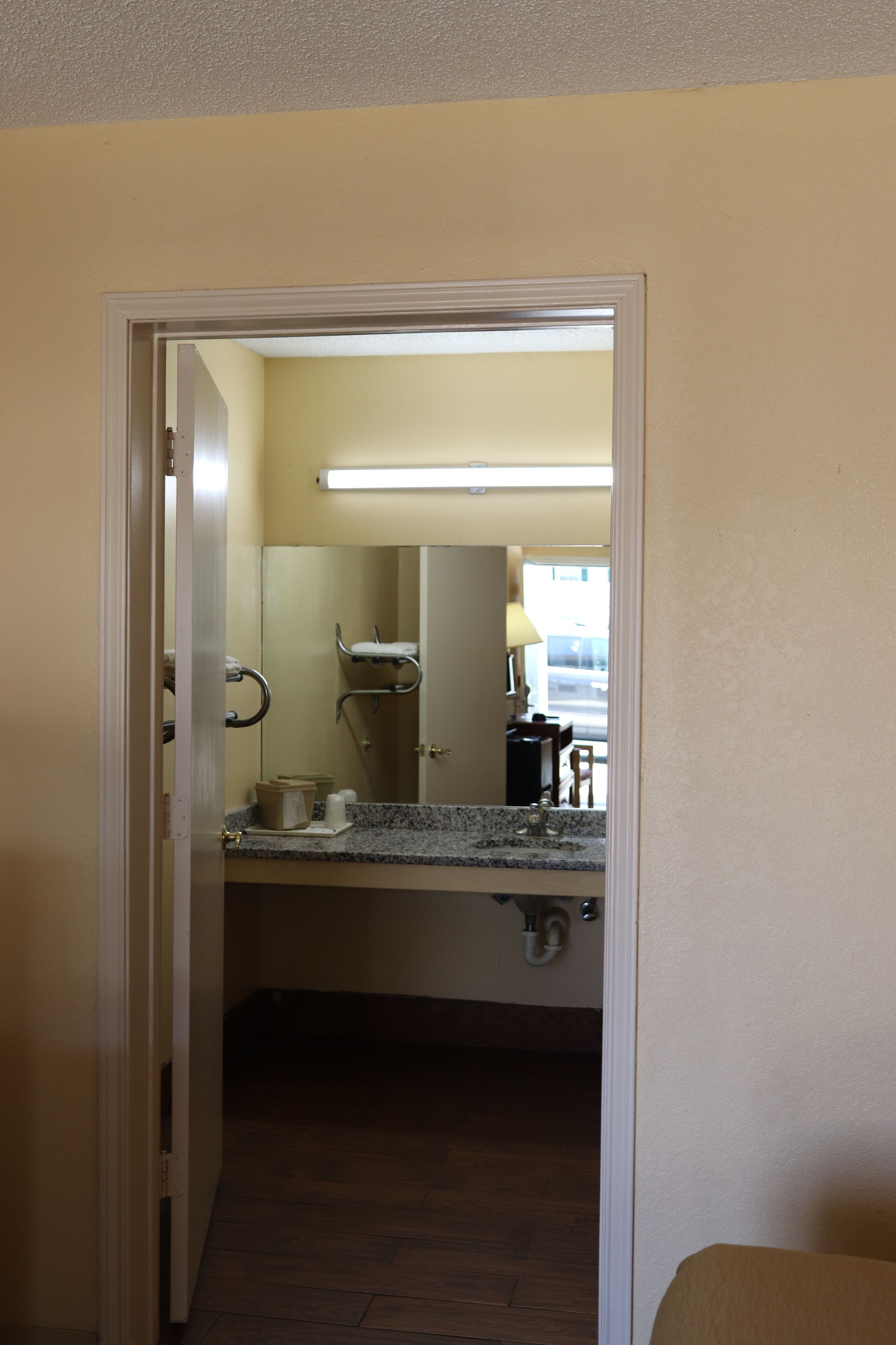 Un baño con lavamanos, espejo y perchero para toallas.