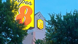 A Super 8 hotel with a prominent sign, a clear entrance, and a building facade with windows and a door. - Super 8 by Wyndham Irving/DFW Apt/North (Irving)