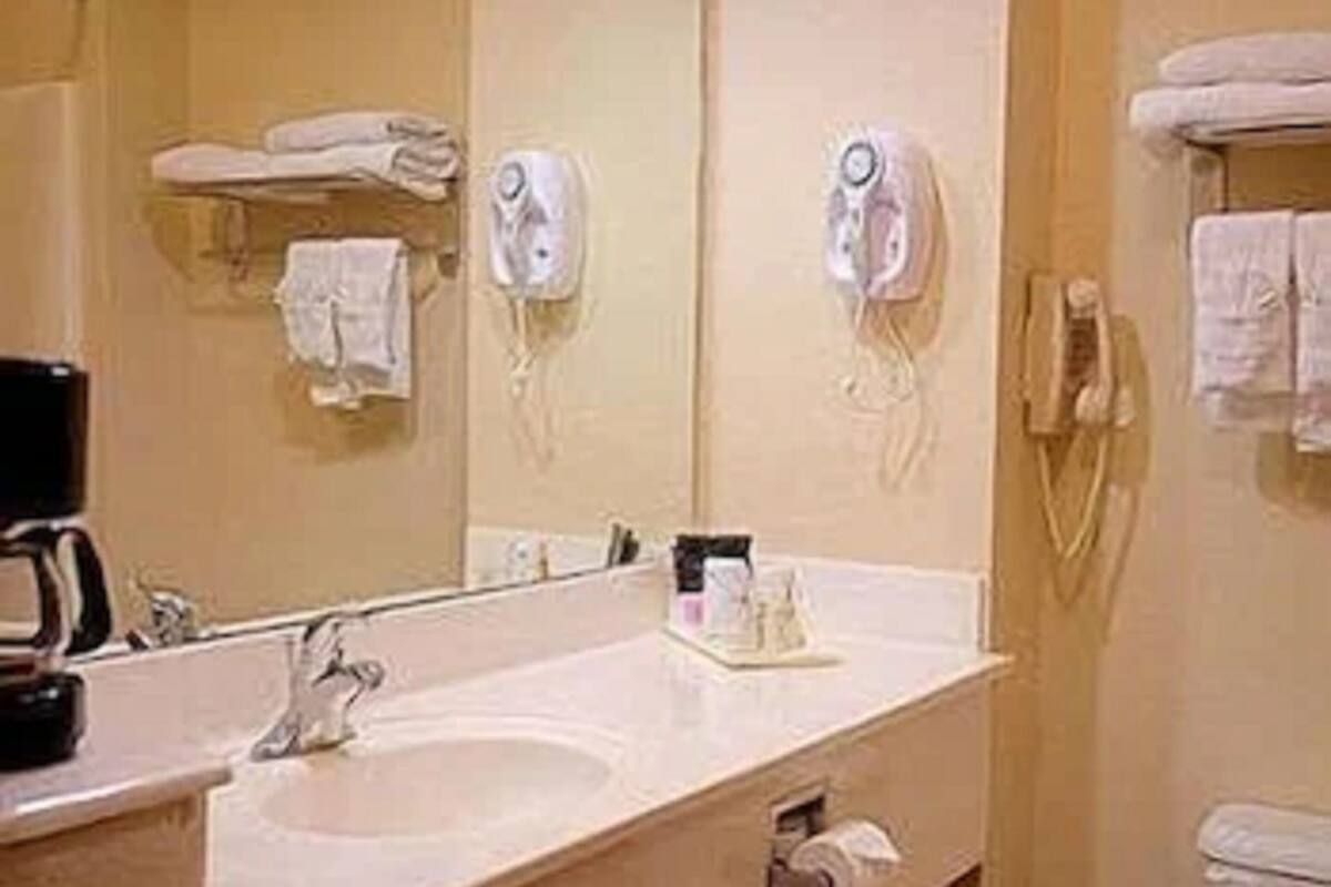 A bathroom with a sink, mirror, towel rack, and a hairdryer.