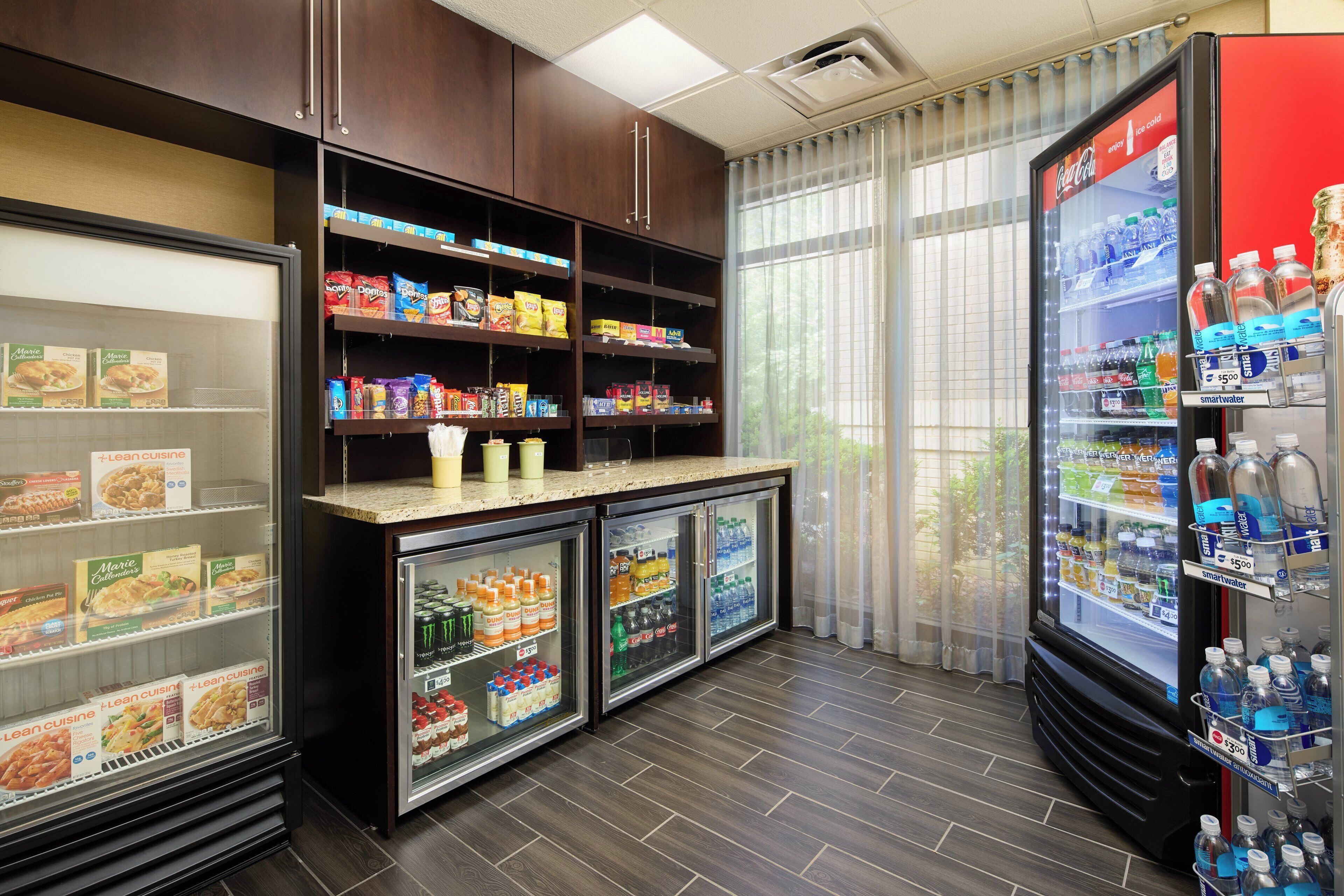 A self-service food and beverage area with refrigerated cases and shelves stocked with snacks and drinks.