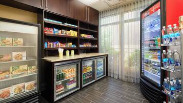 A self-service food and beverage area with refrigerated cases and shelves stocked with snacks and drinks.