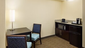 Habitación de hotel compacta con comedor que incluye una mesa, dos sillas, un microondas, un refrigerador y una cafetera.