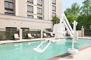 A swimming pool with a diving board and lounge chairs, surrounded by a brick building and a fence. - Holiday Inn Express & Suites Alpharetta - Windward Parkway by IHG (Alpharetta)
