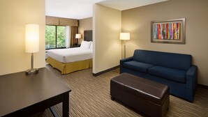 Una habitación de hotel con una cama, un sofá, una mesa y un cuadro en la pared.