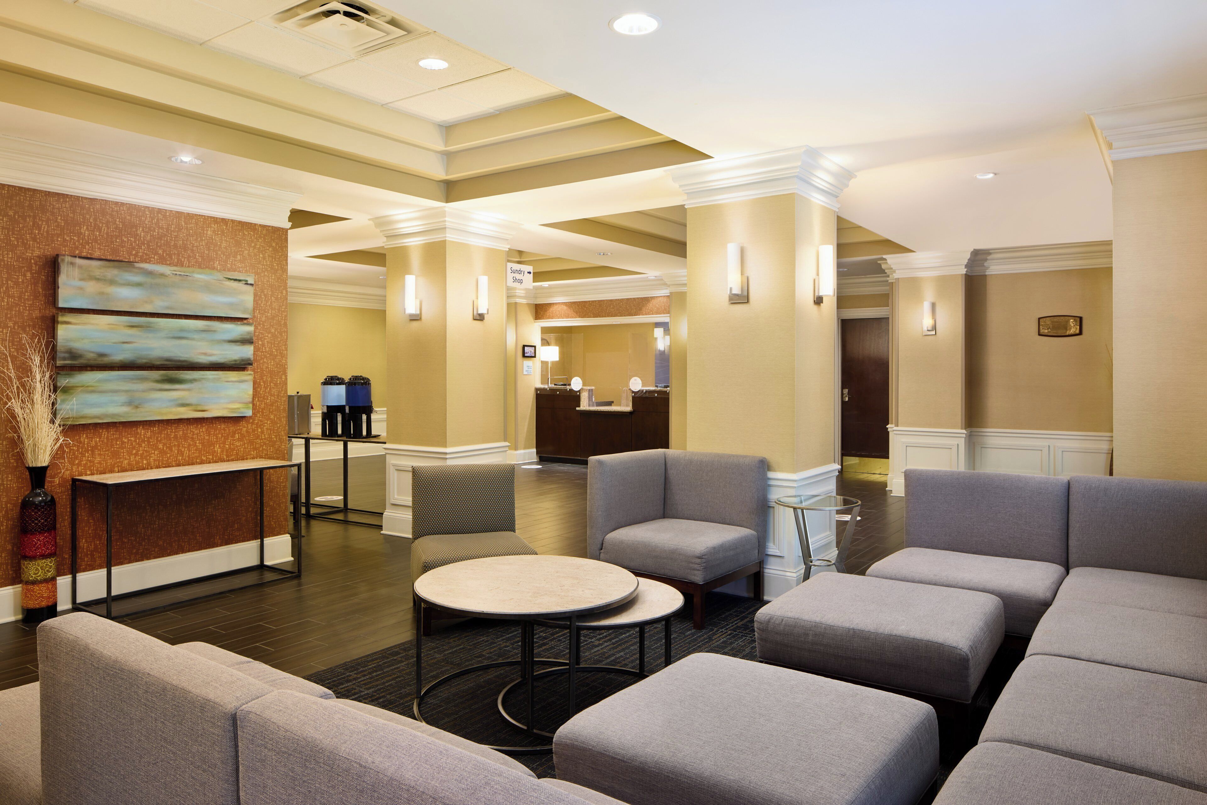 A hotel lobby with seating areas, a reception desk, and a painting on the wall.