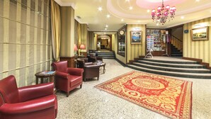 A hotel lobby with leather chairs, a patterned carpet, a chandelier, and a staircase leading to the upper floors. - Grand Yavuz Hotel (Istanbul)