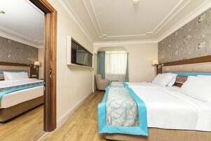 Habitación de hotel con dos camas, un televisor, un escritorio y una silla.