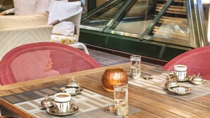 A dining area with a wooden table set for two, featuring a coffee service set, a glass of water, and a decorative vase. - Grand Yavuz Hotel (Istanbul)