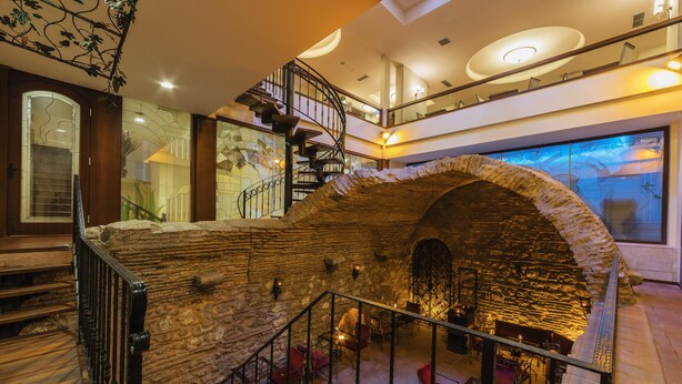 A multi-level interior with a stone archway, a spiral staircase, and a seating area with red chairs. - Grand Yavuz Hotel (Istanbul)