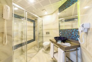 Un baño moderno con ducha de vidrio, inodoro, lavamanos y espejo.