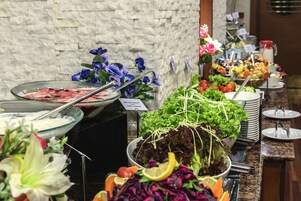 A buffet with various food items and fresh flowers.
