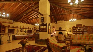 Un interior tradicional con vigas de madera, un candelabro, un conjunto de sofás y una alfombra estampada.