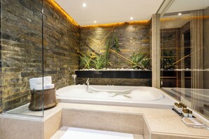 A modern bathroom with a stone wall, a large bathtub, and a glass shower enclosure. - AHC Old City Hotel (Istanbul)