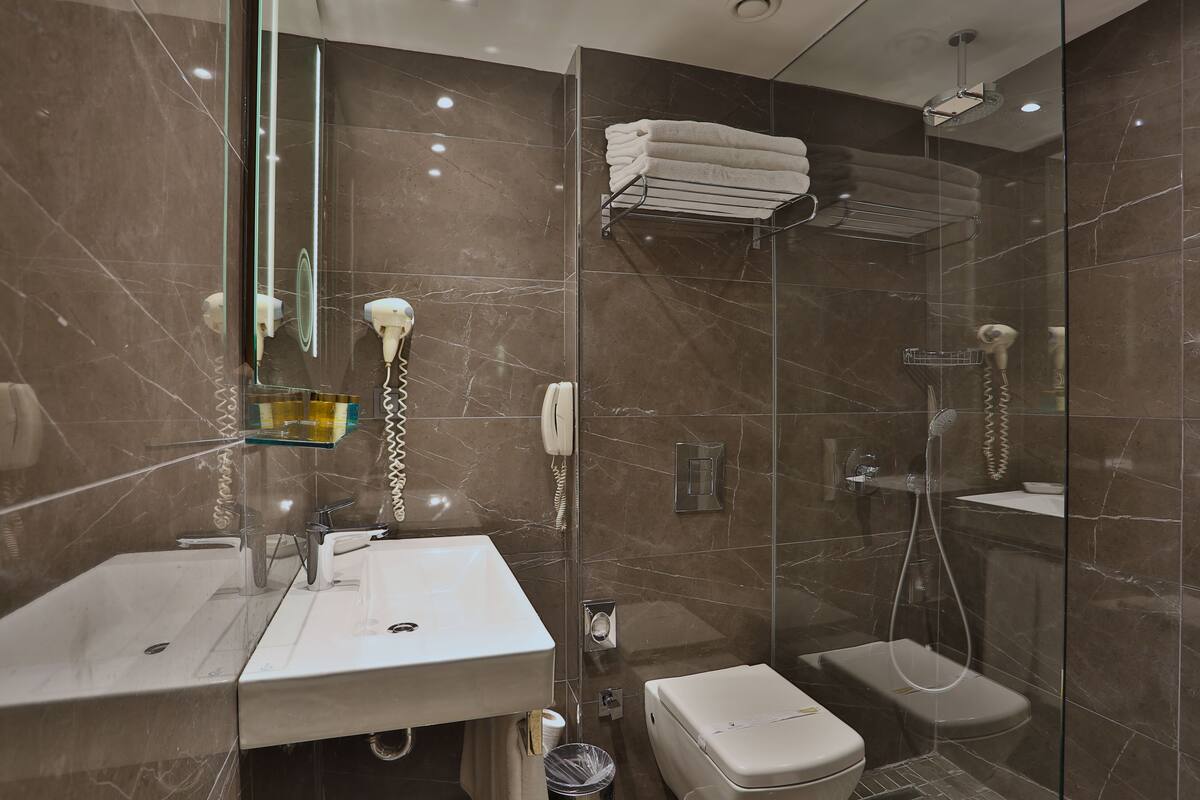 Un baño moderno con ducha de vidrio, lavamanos blanco y un inodoro.