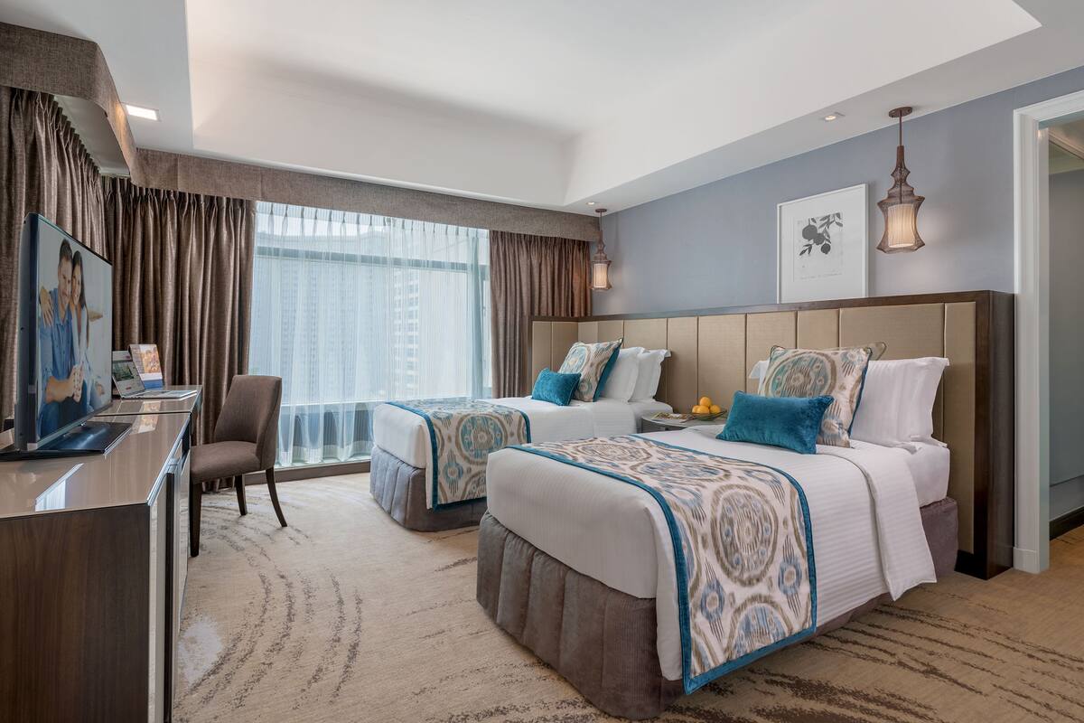 Habitación de hotel con dos camas, un escritorio y una silla.