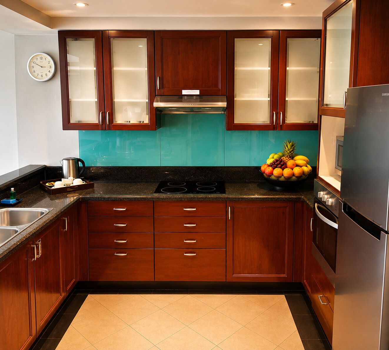 A modern kitchen with wooden cabinets, a stainless steel refrigerator, and a fruit bowl on the counter.