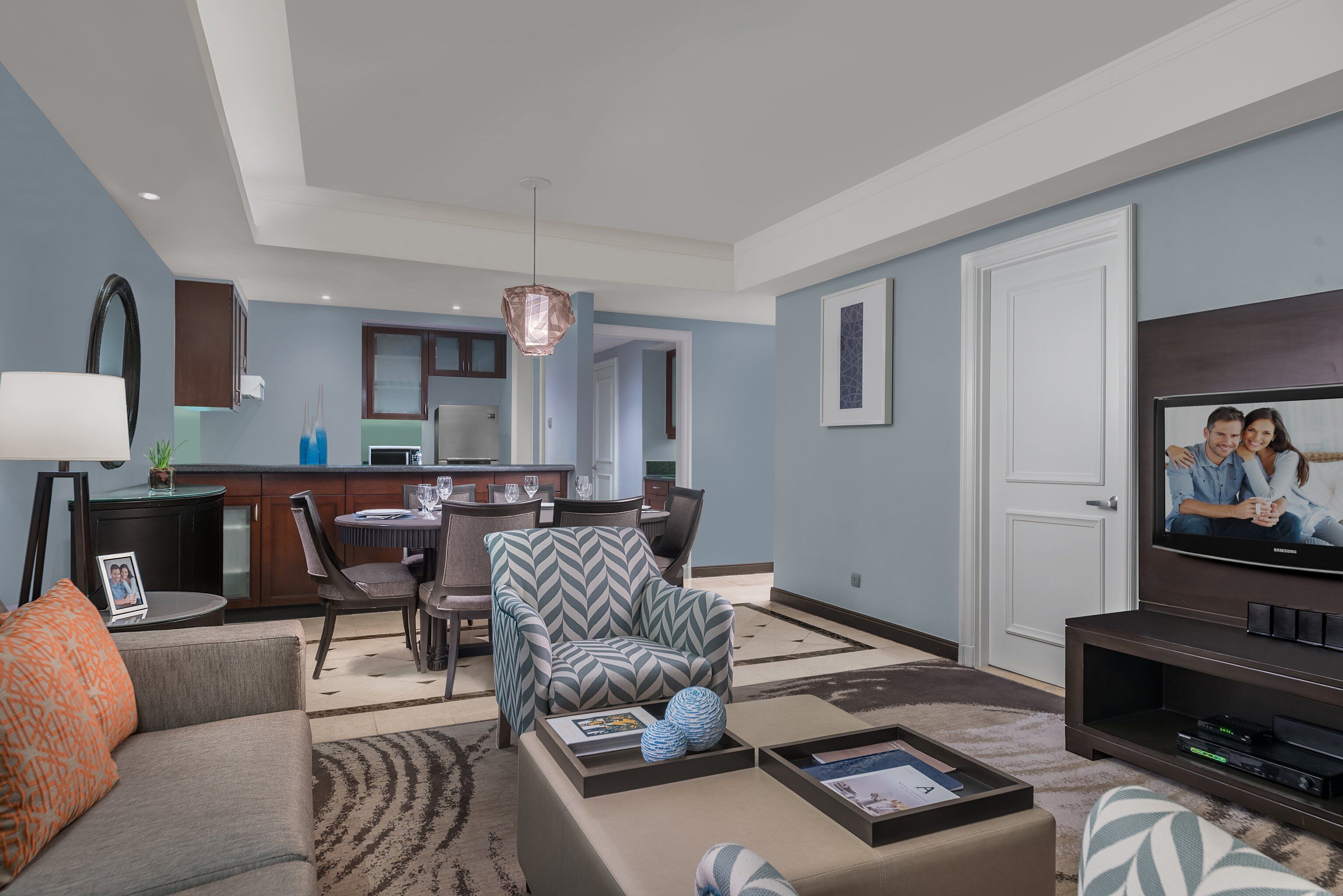 A modern living room with a sofa, armchair, coffee table, and a television.