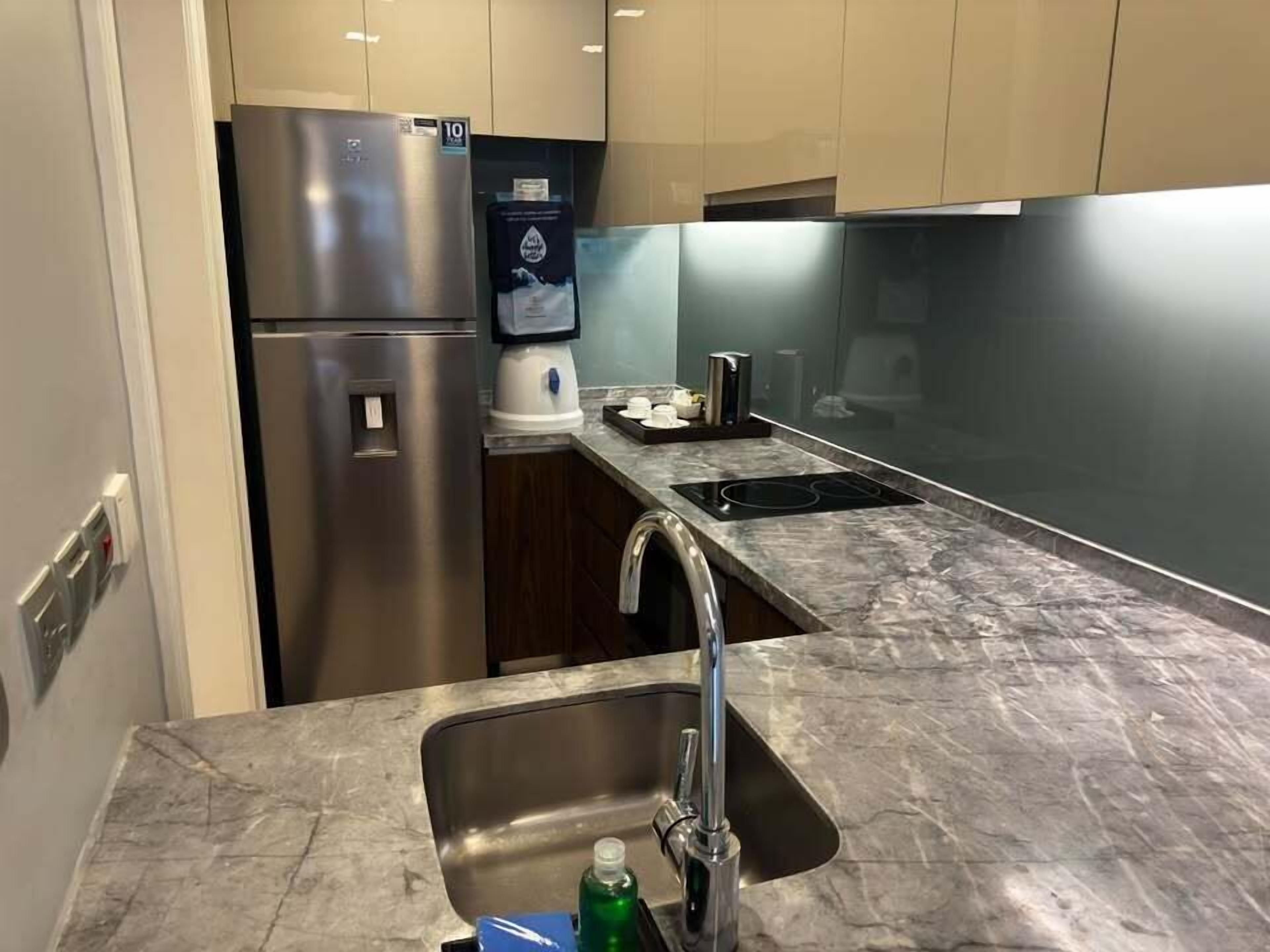 A modern kitchen with stainless steel appliances, a marble countertop, and a built-in sink.