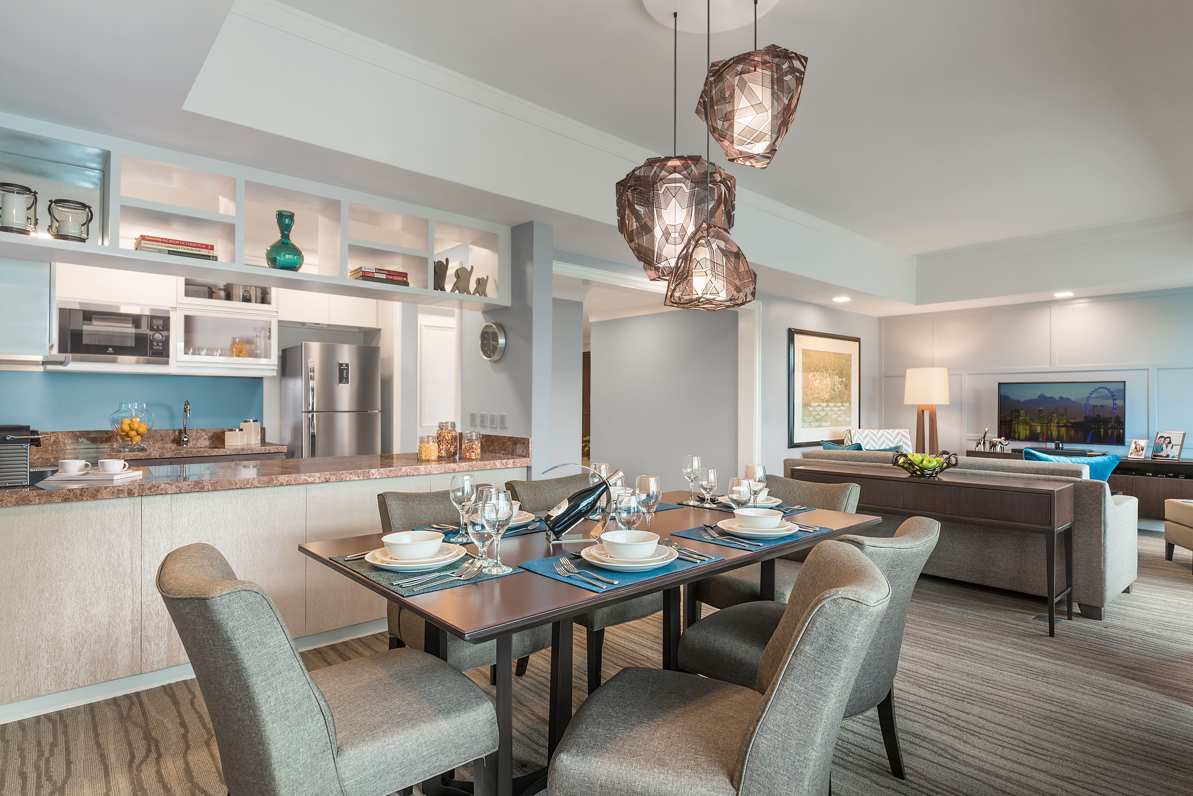 A modern kitchen with a dining area, featuring a central island, built-in appliances, and pendant lighting.