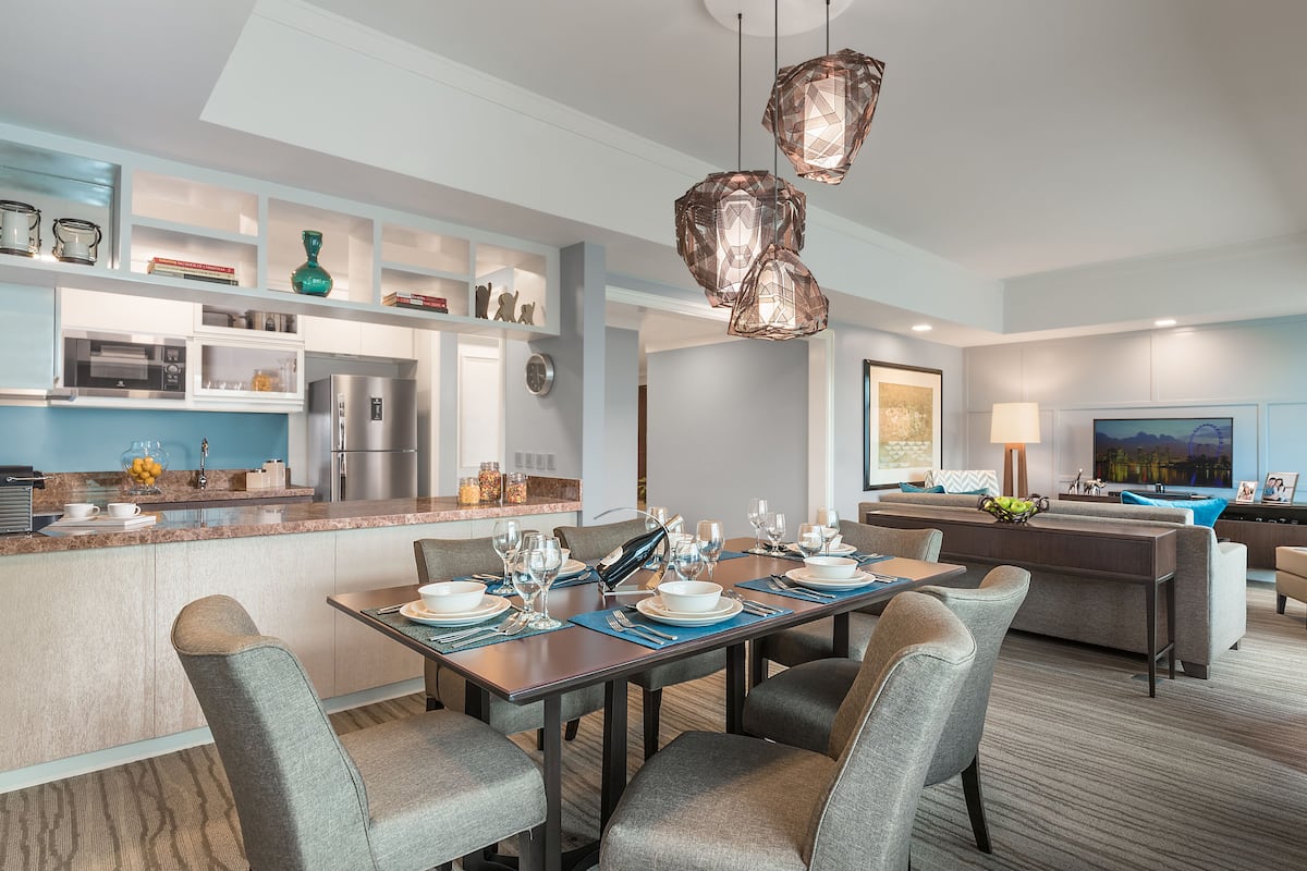 Una cocina moderna con comedor, que cuenta con una isla central, electrodomésticos integrados e iluminación colgante.