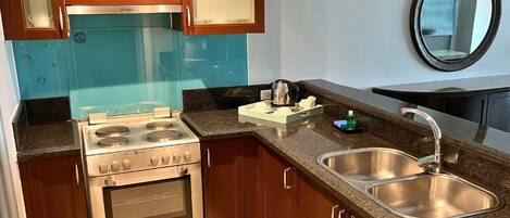 A kitchen with a stove, sink, and wooden cabinets.