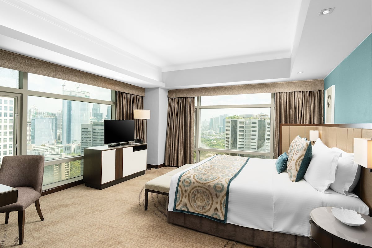 Una habitación de hotel moderna con una cama grande, un escritorio y un televisor.