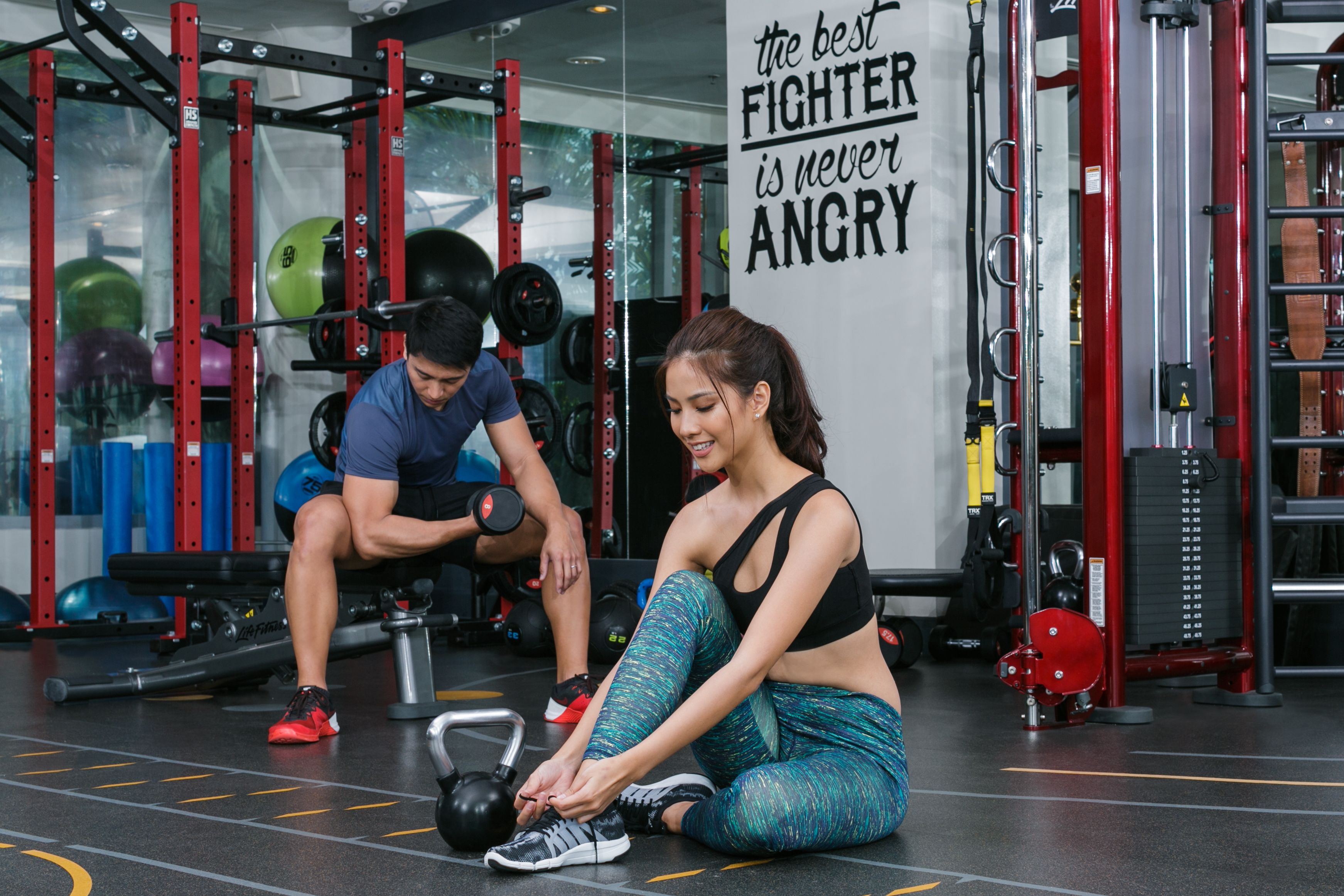 A gym with weightlifting equipment and a motivational quote on the wall.
