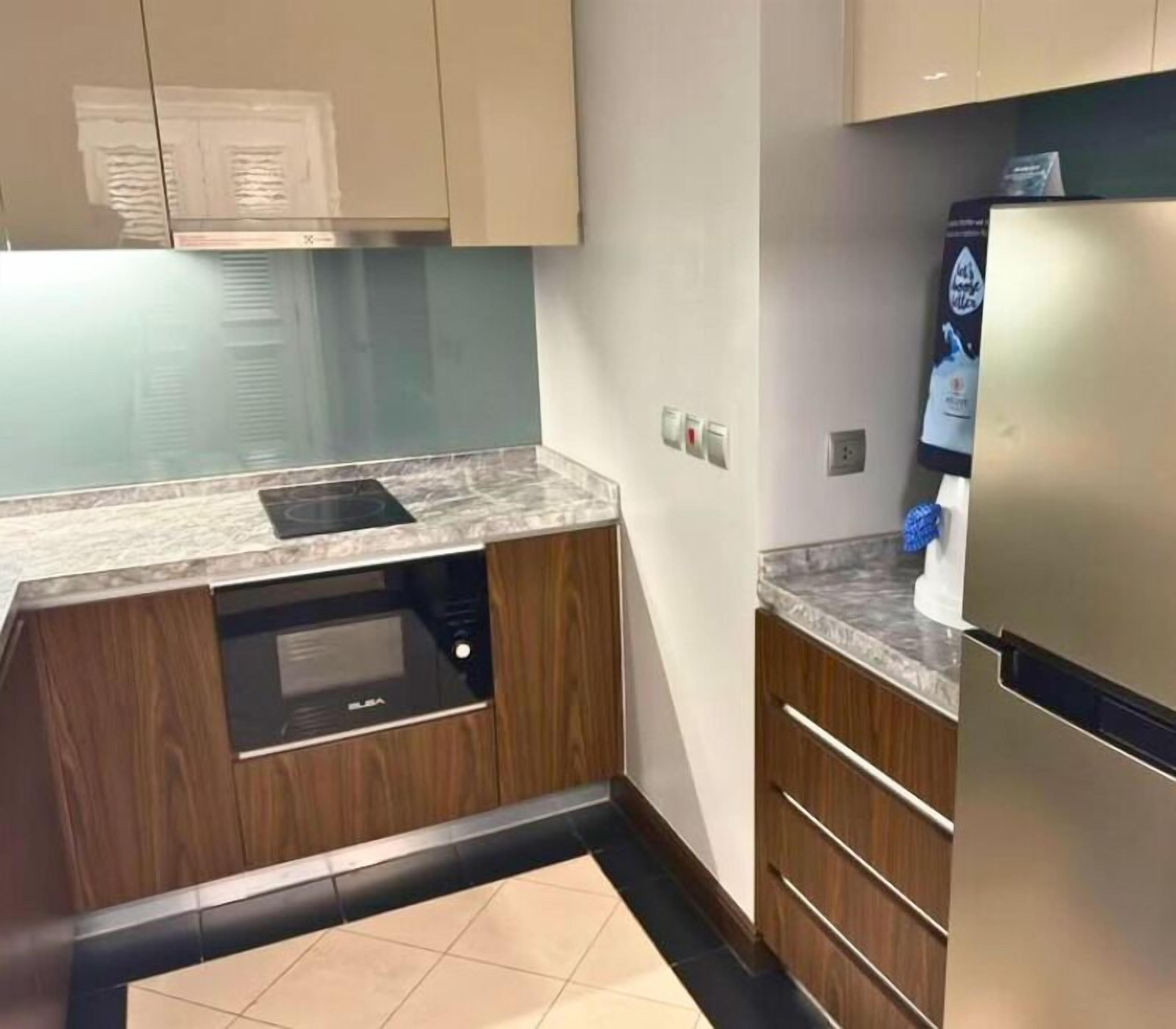 Una cocina con microondas integrado, refrigerador y alacenas de madera.