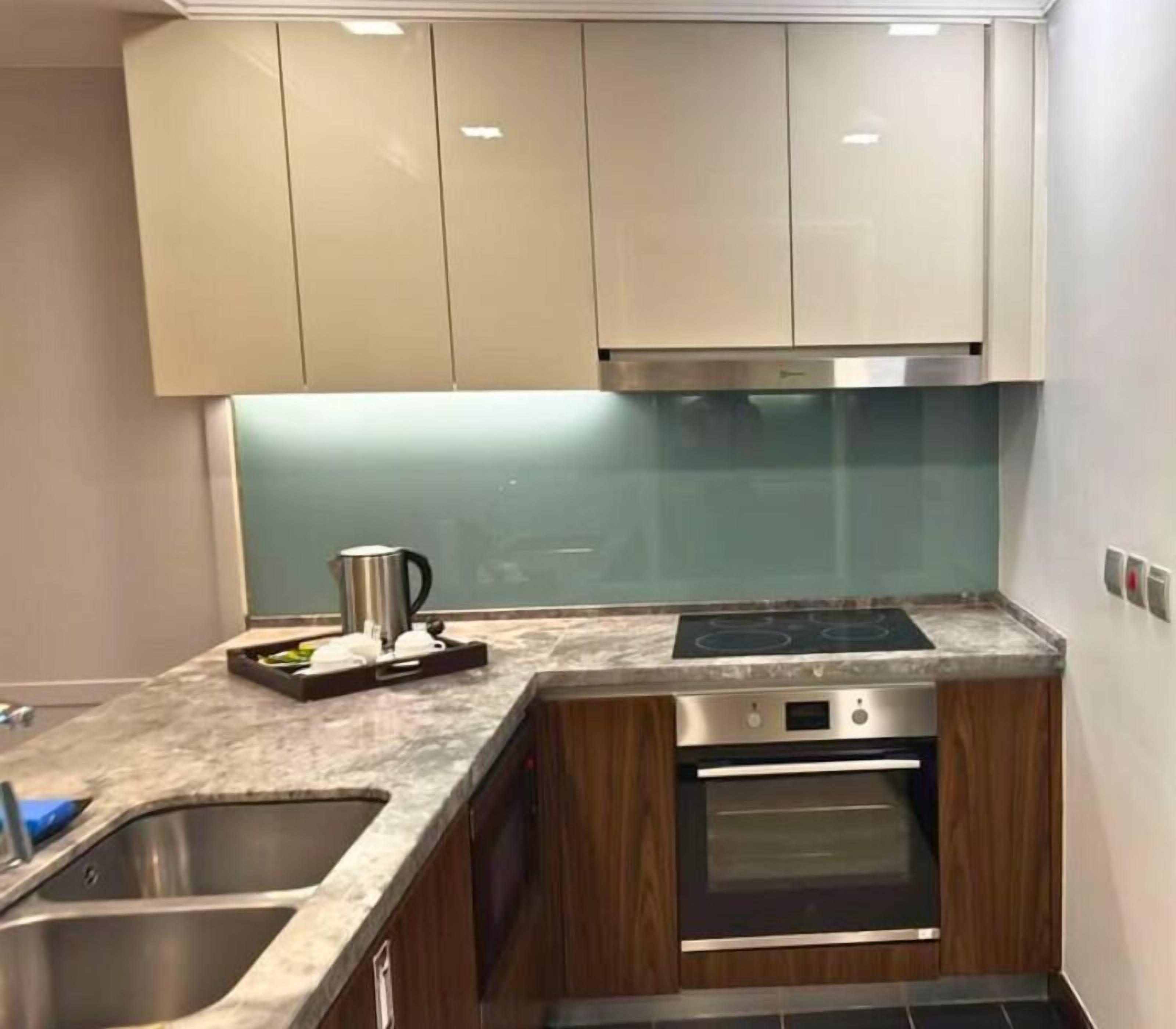 A kitchen with a built-in oven, stainless steel sink, and a microwave.