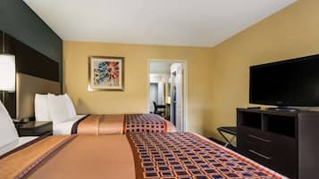 Una habitación de hotel con dos camas, un televisor, un escritorio y una silla.