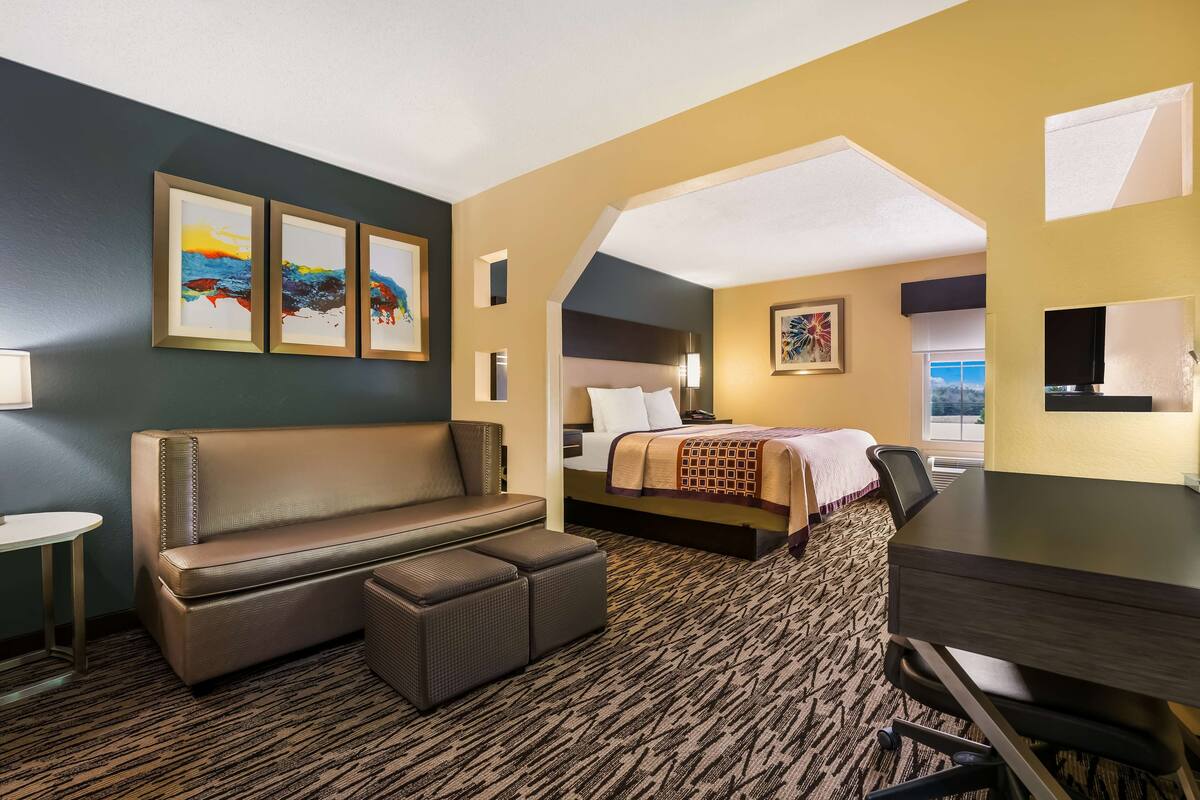 A hotel room with a sofa, a bed, a desk, and a view of the outdoors.