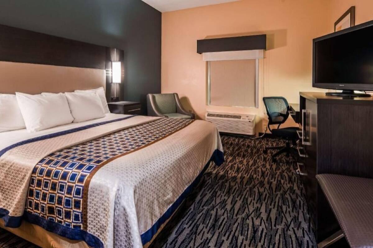 A hotel room with a bed, a television, a desk, and a chair.