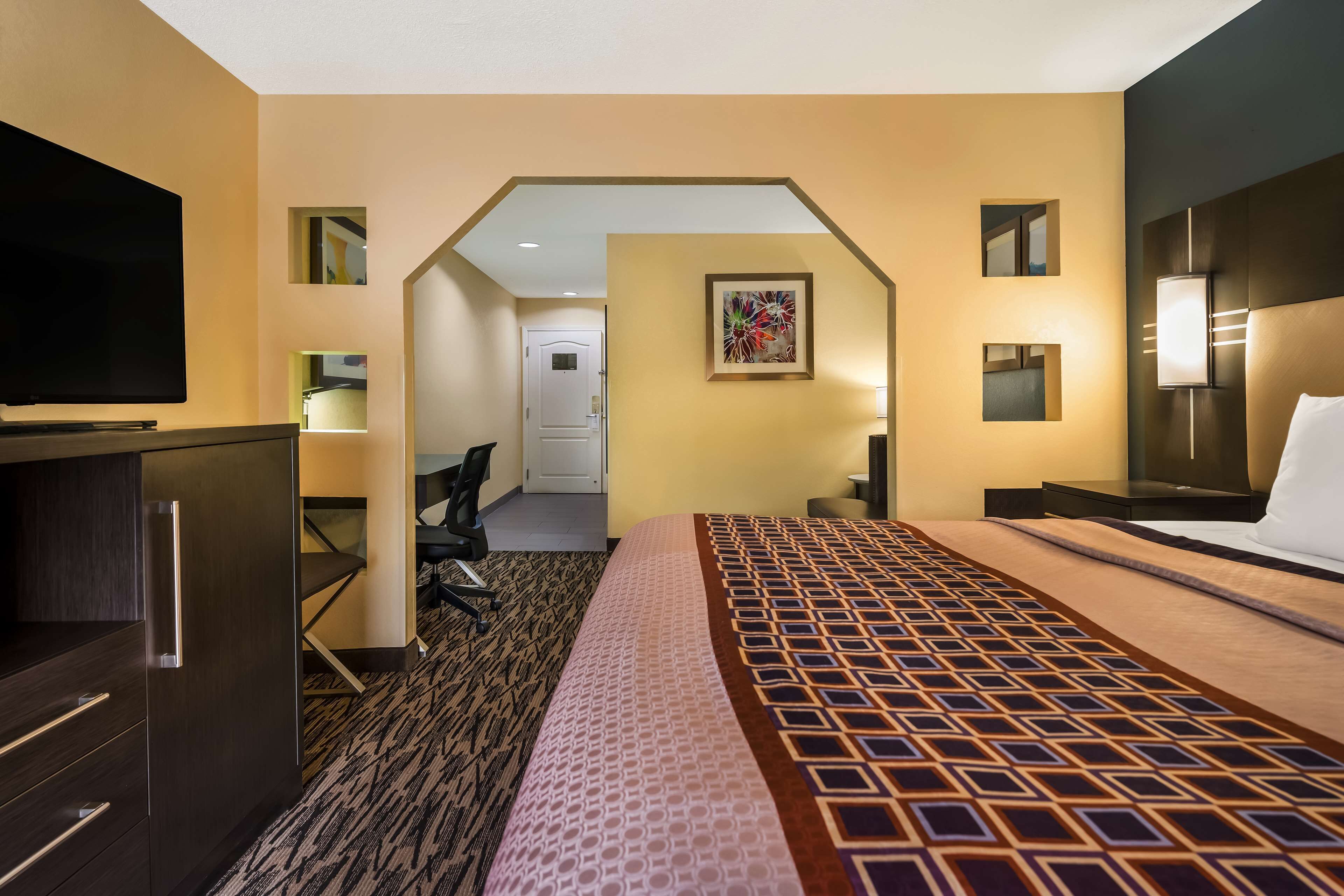 A hotel room with a bed, a TV, a desk, and a chair.