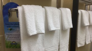 A row of white towels hanging on a rack in a bathroom. - Days Inn by Wyndham Athens, GA (Athens)