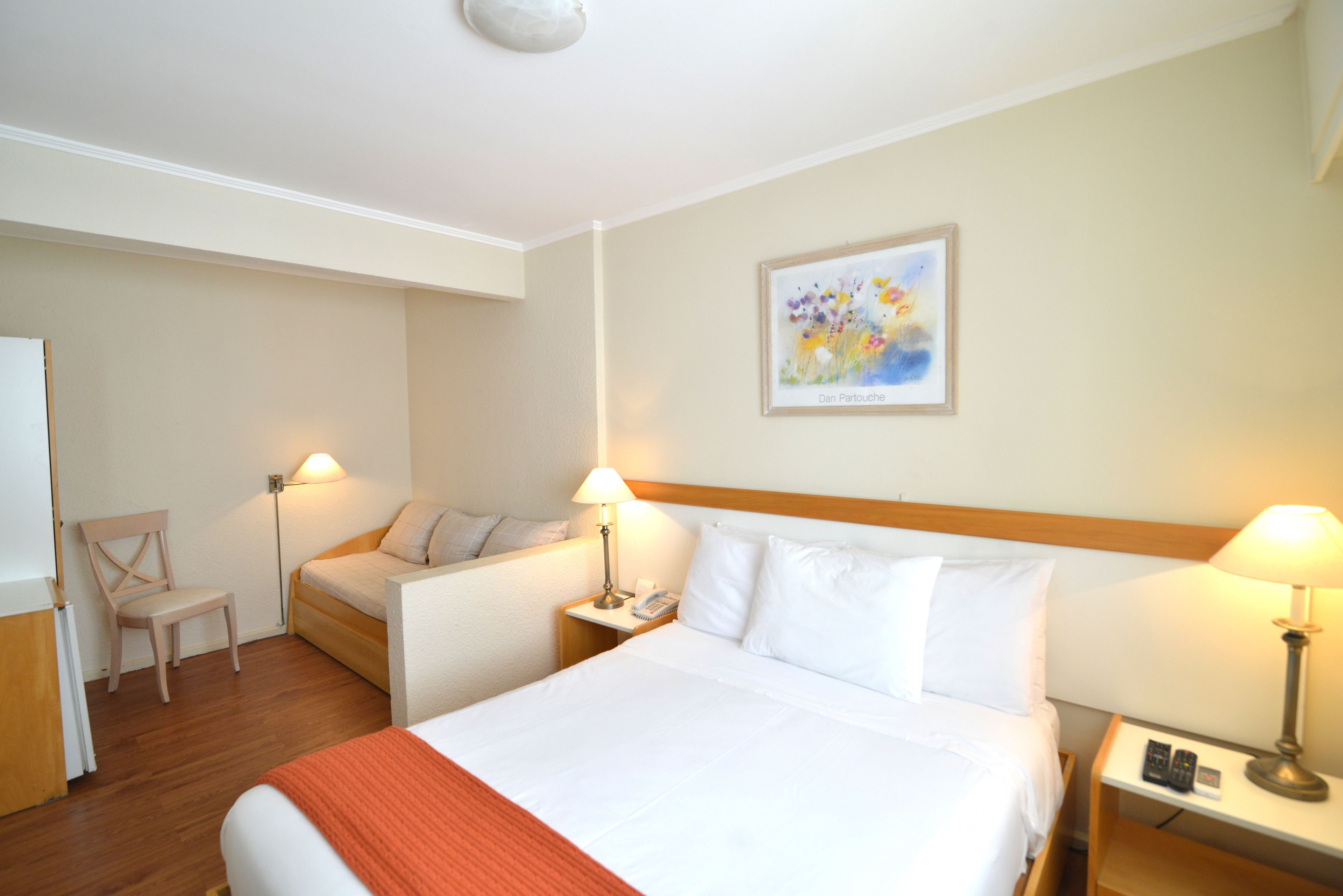 A hotel room with a large bed, two bedside tables with lamps, a chair, and a painting on the wall.