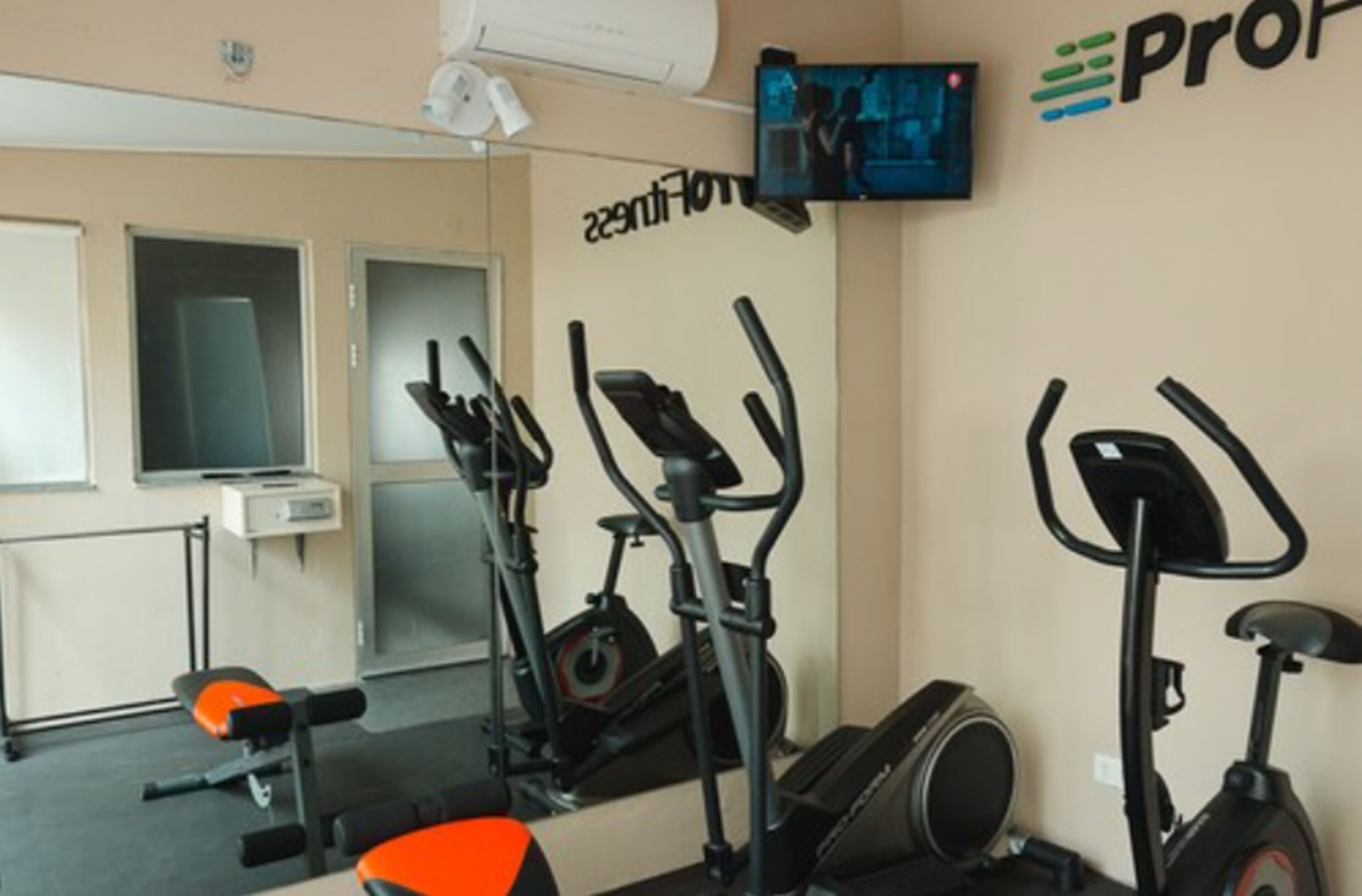 Un gimnasio con equipo de ejercicio, un televisor y un cartel en la pared.