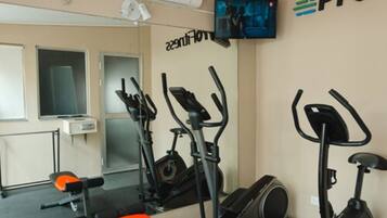 Un gimnasio con equipo de ejercicio, un televisor y un cartel en la pared.