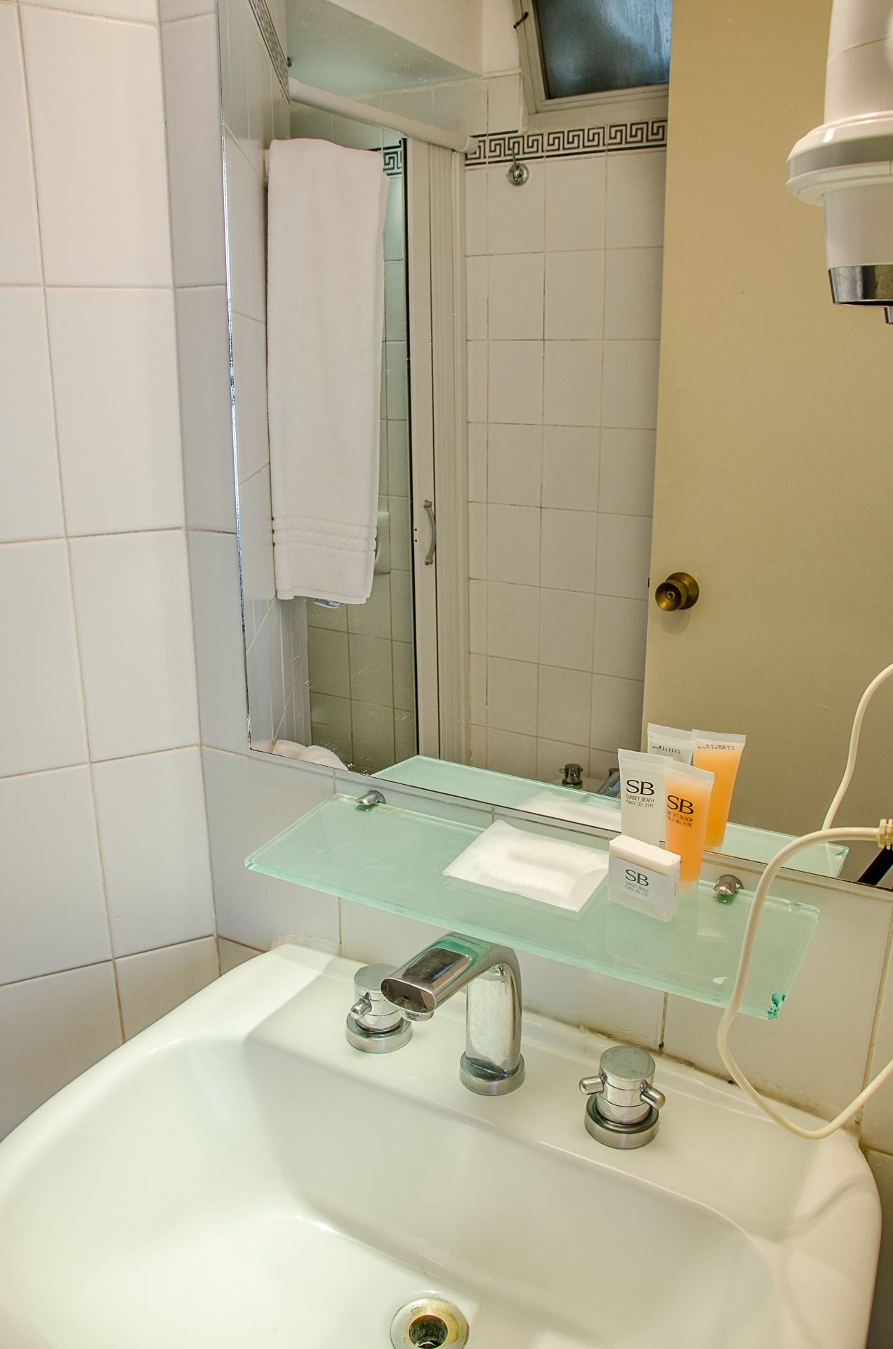 A bathroom with a glass sink, a mirror, and toiletries.