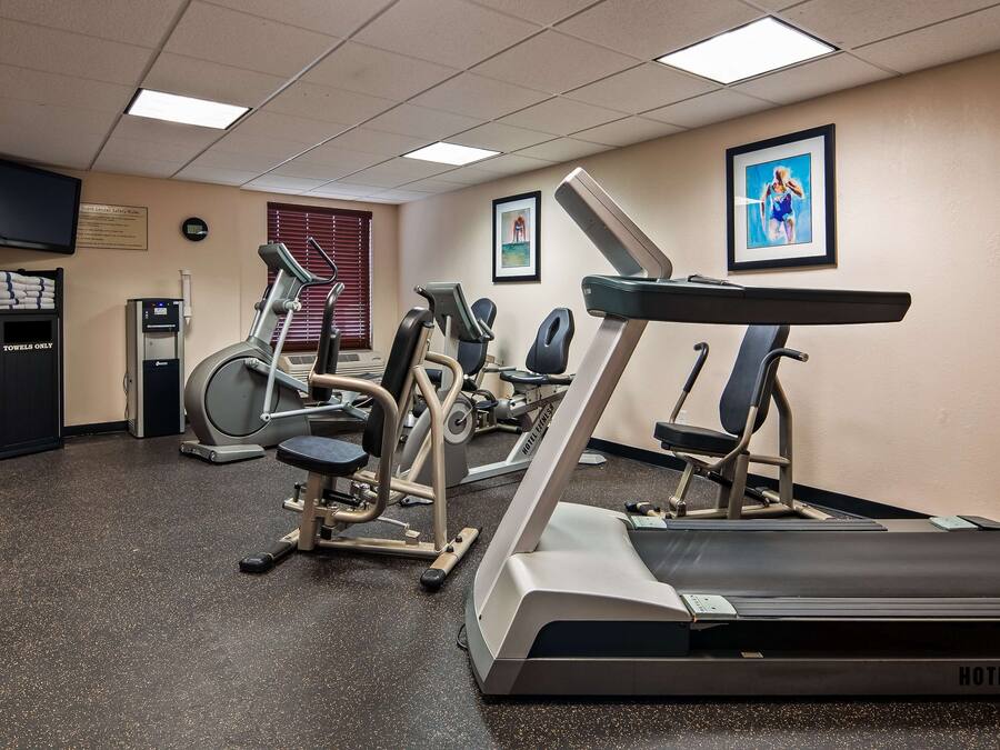 A hotel fitness center with exercise equipment, a treadmill, and a wall-mounted TV.