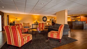 Un vestíbulo de hotel con sillones a rayas, una mesa redonda para café, un sofá y un reloj en la pared.