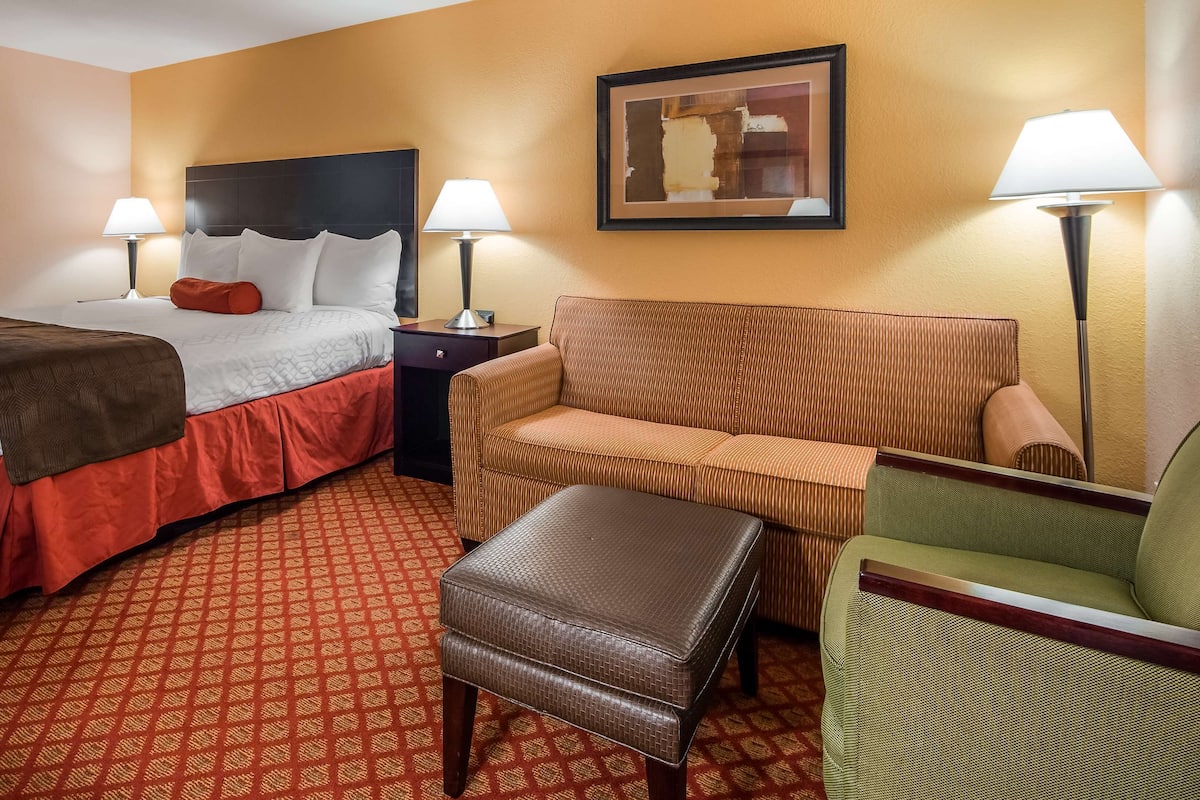 Une chambre d’hôtel avec deux lits, un canapé, un pouf et deux tables de chevet avec des lampes.