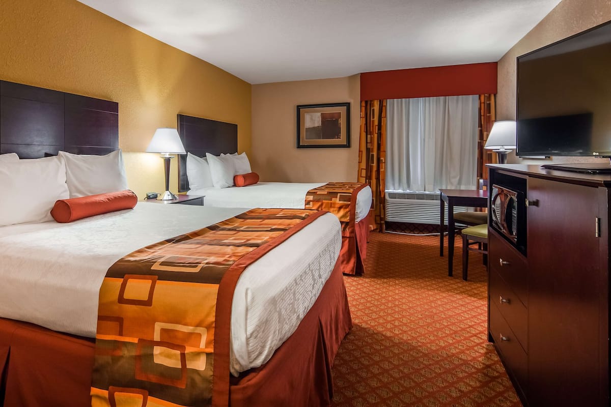 Une chambre d’hôtel avec deux lits, une télévision, un bureau et une chaise.