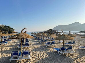 En la playa, sillas reclinables de playa, sombrillas, toallas de playa