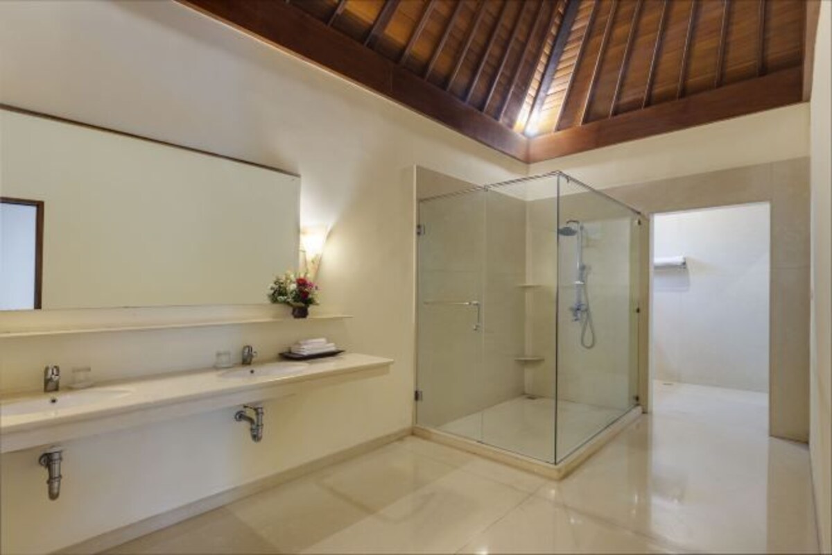 A modern bathroom with a glass-enclosed shower, a large mirror, and a wooden ceiling.