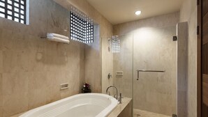 A modern bathroom with a freestanding bathtub, a glass-enclosed shower, and a small flower arrangement on the vanity. - Rijasa Agung Resort Villas (Ubud)